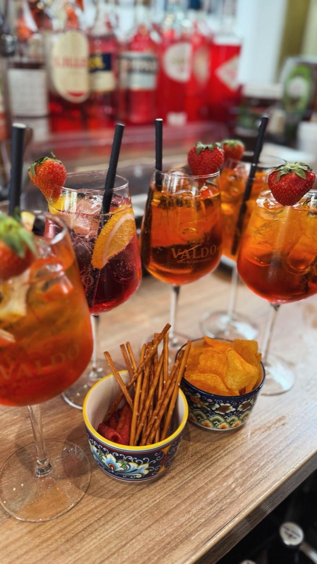 Verschiedene Spritz-Drinks mit Erdbeeren an der Bar